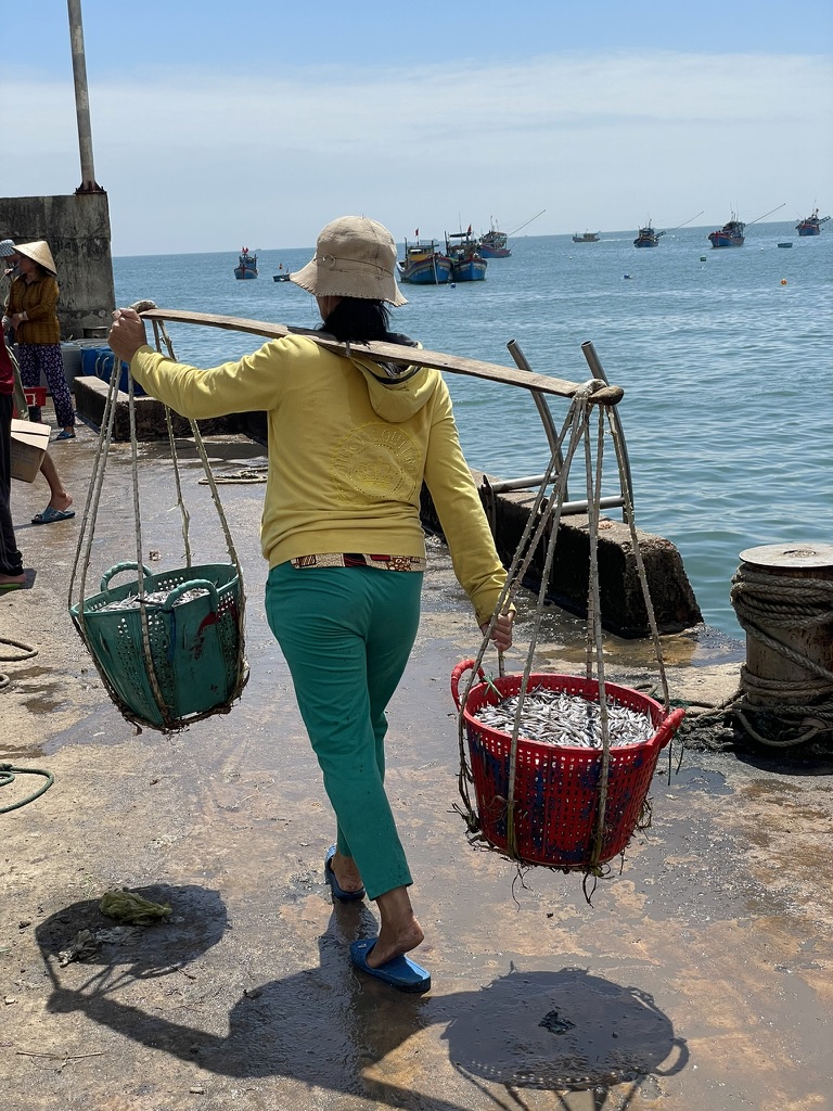 port de Nhon Ly femme portant les paniers de poisson